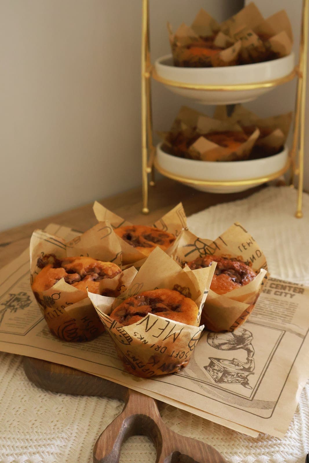 Muffins wrapped in paper on a wooden board